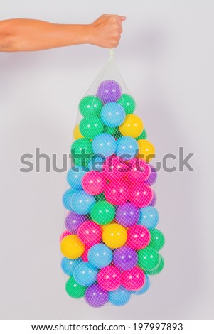 Right hand hold Multicolor plastic ball inside net on white background
