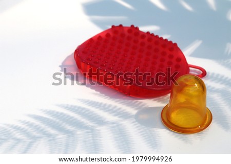 Yellow vacuum massage jar and red silicone massage brush on a white background. High quality photo