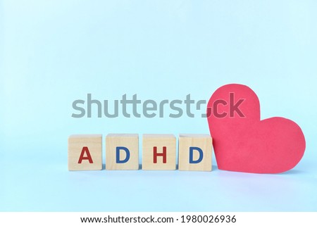 Love and support kids with ADHD or attention deficit hyperactivity disorder concept. ADHD letters on wooden blocks beside a red heart shape with copy space.