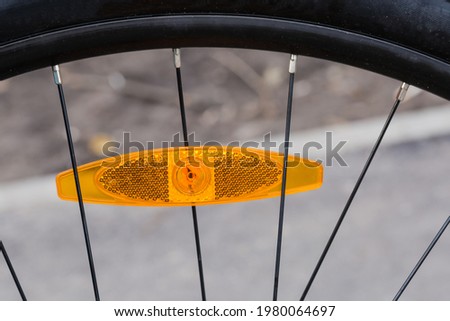 Fragment of bicycle wheel with plastic reflector orange color installed between the spokes
 Royalty-Free Stock Photo #1980064697
