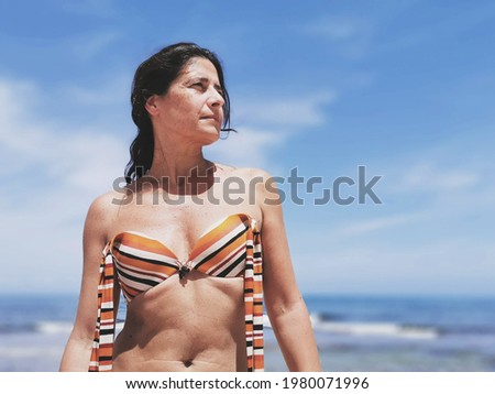 Smiling beautiful middle age brunette spanish woman sunbathing on a beach of Spain