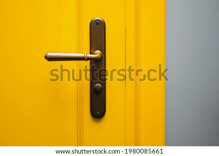 Yellow door with a bronze door handle close-up. Bright Interior details