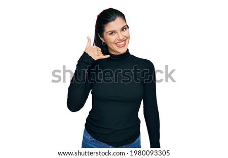 Young hispanic woman wearing casual clothes smiling doing phone gesture with hand and fingers like talking on the telephone. communicating concepts. 