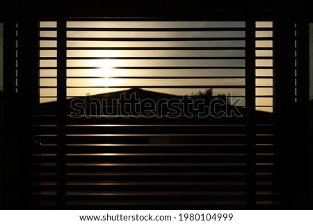Abstract blurred background of the warm orange light of the sun escaping through the windows through the blinds. In the atmosphere during the evening near dusk. Light through the window. Royalty-Free Stock Photo #1980104999