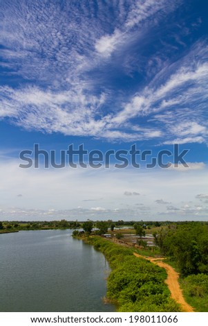 View the gravel road near the water with a blue sky background.