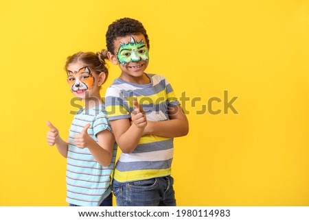 Funny children with face painting on color background Royalty-Free Stock Photo #1980114983