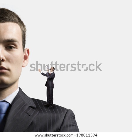 Miniature of businessman screaming in megaphone standing on boss shoulder