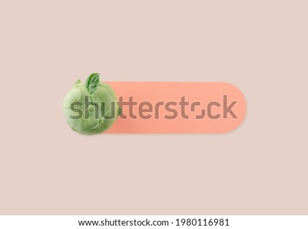 Green bulbous kohlrabi on pale orange sheet of paper on the pastel beige background. Summer vegetable healthy food minimal flat lay with copy space. On-off note card creative concept. 