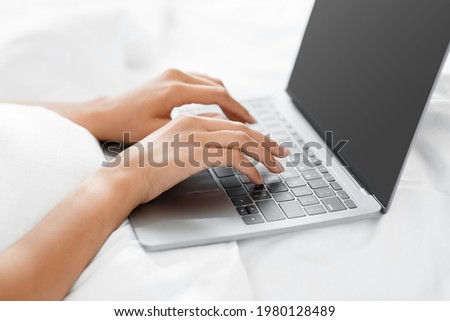 Remote work from home, work in bedroom, social networks and chat in morning. Millennial african american woman on bed, typing on laptop with empty screen in bedroom, close up, cropped, free space