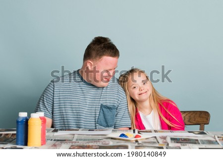 Cute siblings with down syndrome playing with paint