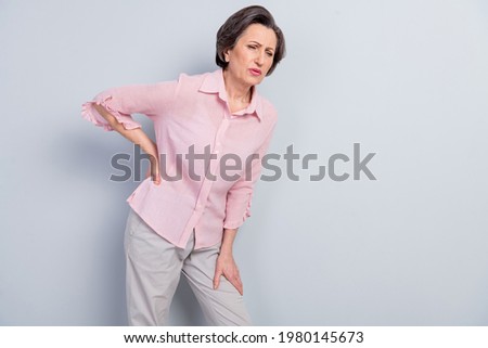 Photo of unhappy sad upset old woman hold hand back spine paid ill disease isolated on grey color background Royalty-Free Stock Photo #1980145673