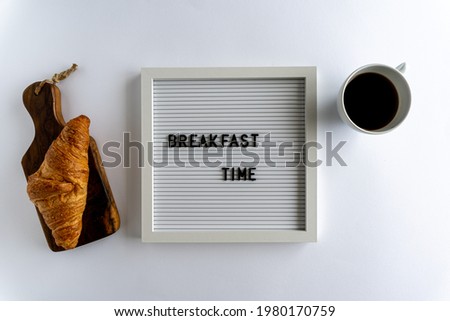 Letterboard With Words That Spell Breakfast Time, with a croissant and a cup of coffee , on a white background, horizontal