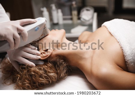 Hardware cosmetology and facelift concept. SMAS face lifting ultrasound procedure carried out in beauty clinic, ultrasonic device rejuvenate women facial skin, enhance collagen production in derma