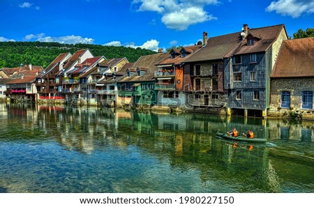 Canoe navigation along the Loue river which is overlooked by the characteristic houses. Town of Ornans in the Doubs department, Burgundy-Franche-Comte region, France. HDR image Royalty-Free Stock Photo #1980227150