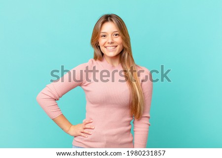 young pretty woman smiling happily with a hand on hip and confident