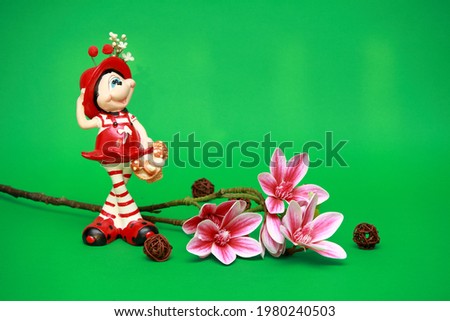 Spring bouquet of orchid flowers. On a beautiful gentle green background. Souvenir red figurine of a fairy girl. Macro. Postcard with floral wallpaper. Romantic artistic image, place for tex