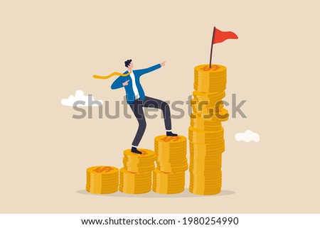 Financial goal, wealth management and investment plan to achieve target, income or salary growth concept, cheerful businessman step climbing money coin stack aiming to achieve target flag on top.  Royalty-Free Stock Photo #1980254990