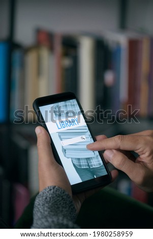 a young caucasian man, at home, searches an ebook to lend on an online library with his smartphone, with a simulated search engine in its screen