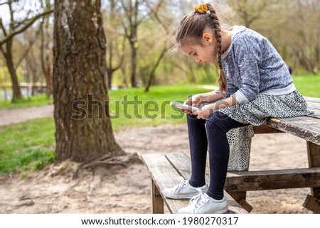 A little girl checks her phone, not paying attention to the beautiful nature around.