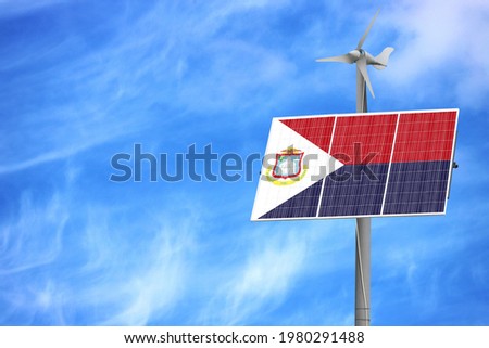 Solar panels against a blue sky with a picture of the flag of Saint Martin