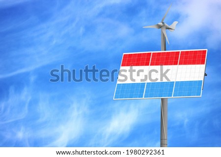 Solar panels against a blue sky with a picture of the flag of Luxembourg