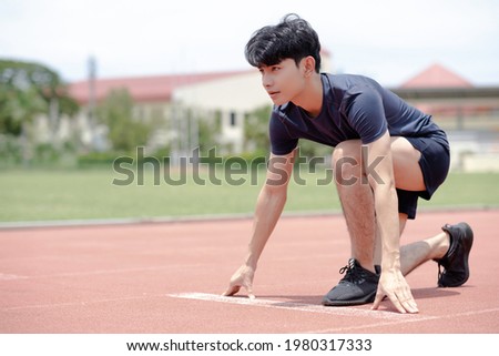 An asian man ready to run at start point with concentration emotion at sport field background.
