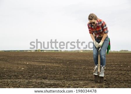 Young woman standing on sharp shovel looking down