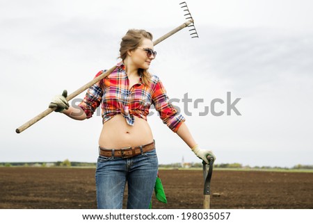 Young woman with rake and shovel at shirt