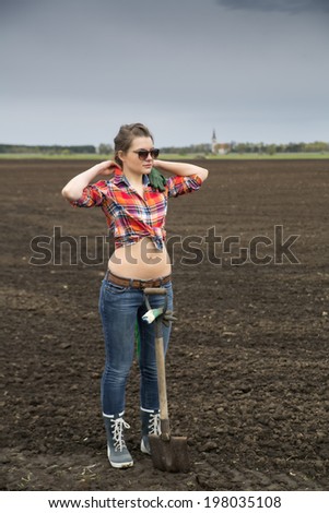 Young woman and sharp shovel on cultivated field