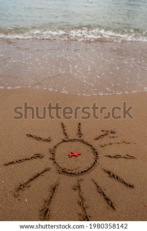 figure of a red plane and painted the sun on the sand on the coast. rest and tourism by plane to the sea. A picture of the sun and the symbol of the plane by the sea