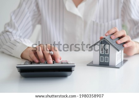 close up hand with house model for real estate check and summary expense of home loan mortgage for refinance plan, insurance or loan real estate. Royalty-Free Stock Photo #1980358907