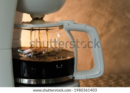coffee pot and coffee is dripping inside. Concrete wall background. photo shooting in warm light Royalty-Free Stock Photo #1980361403