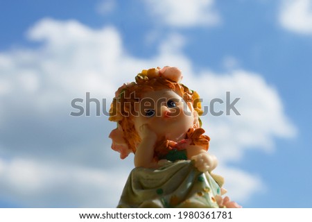 Funny figurine. Angel girl on a background of blue sky.