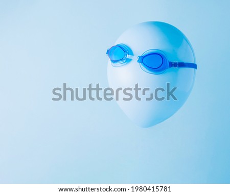 Blue balloon with diving goggles on a pastel blue background. Minimal summer concept.