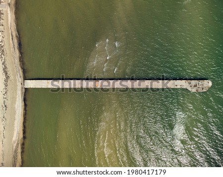 Aerial top view of turquoise water with concrete pier on a Azov sea