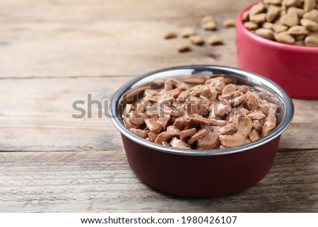 Wet pet food in feeding bowl on wooden table. Space for text Royalty-Free Stock Photo #1980426107