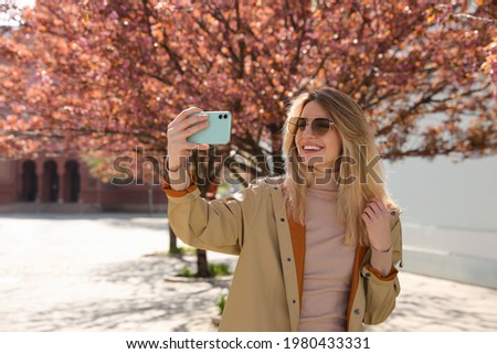 Young woman taking selfie on city street