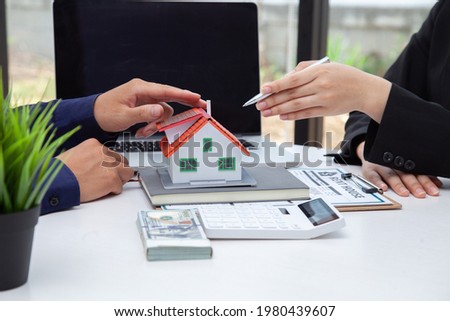 The businessman discusses the terms of the home purchase contract and asks the customer to sign a document to legally enter into the contract. Real estate ideas and home sales with home insurance
