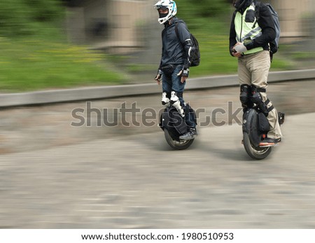 Two people ride electric unicycle along the street  Royalty-Free Stock Photo #1980510953
