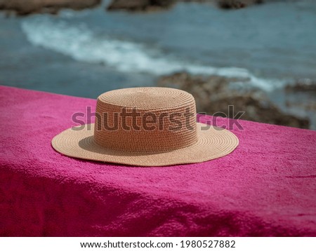 Women's beach hat placed on a rock wall next to the waves of cabo de palos (la manga, Murcia). Vintage image, fashion lifestyle and exotic style. Essence of summer and good weather.