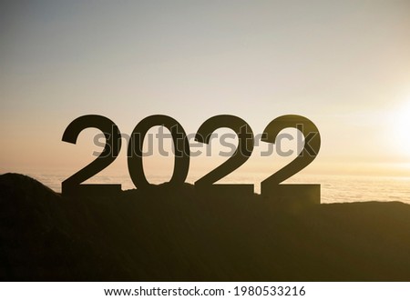 2022 happy new year sign on top of the mountain with sunset, symbol of new success and opportunities