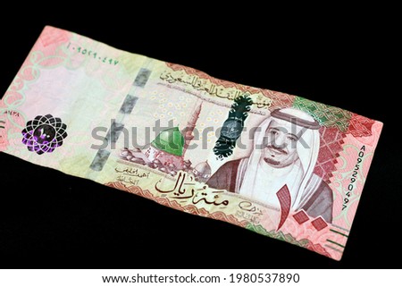 Saudi Arabia 100 riyals banknote, Saudi kingdom one hundred riyals  with the photo of king Salman Bin Abdulaziz and the green dome with The Prophet's Madinah mosque isolated on black background Royalty-Free Stock Photo #1980537890