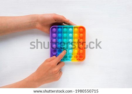 Child's hands playing with colorful pop pit game. Pop it fidget toy. Top view, flat lay. Royalty-Free Stock Photo #1980550715