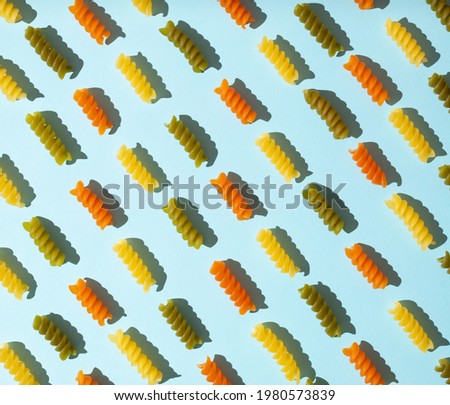 Creative pattern made of spiral macaroni on a pastel blue background.