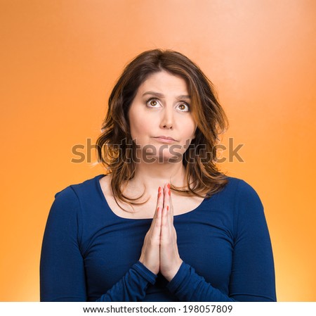 Closeup portrait young woman praying, eyes opened, looking up, hoping for best, asking forgiveness, miracle isolated orange background. Human emotions, facial expression, feelings, life perception