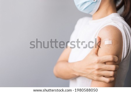 Happy Woman showing her arm with bandage after receiving vaccine. Vaccination, immunization, inoculation and Coronavirus ( Covid-19 ) pandemic Royalty-Free Stock Photo #1980588050