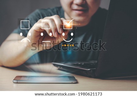 Customer service, Young Asian Businessman give a happy smile and five star shape on a virtual digital screen with smartphone and laptop, the concept of surveying rating satisfaction. Royalty-Free Stock Photo #1980621173
