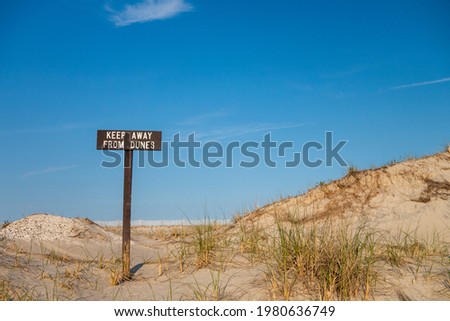 Wooden brown and white beach T sign with words that read keep way from dunes