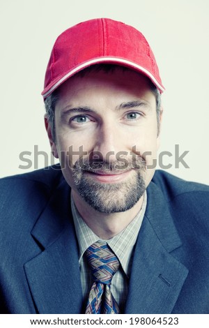 Man formally dressed and groomed with red cap.
