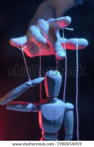The human hand with marionette on the strings. Concept of control. Royalty-Free Stock Photo #1980654059
